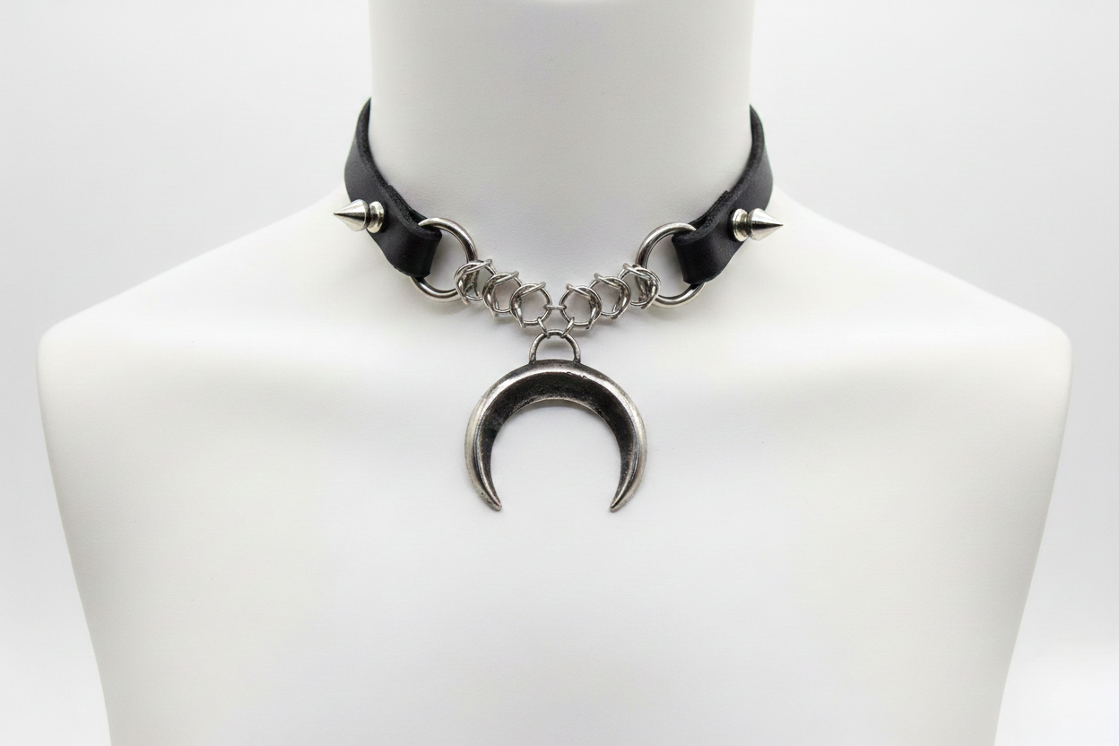 Black leather choker with silver crescent moon pendant on a mannequin bust.