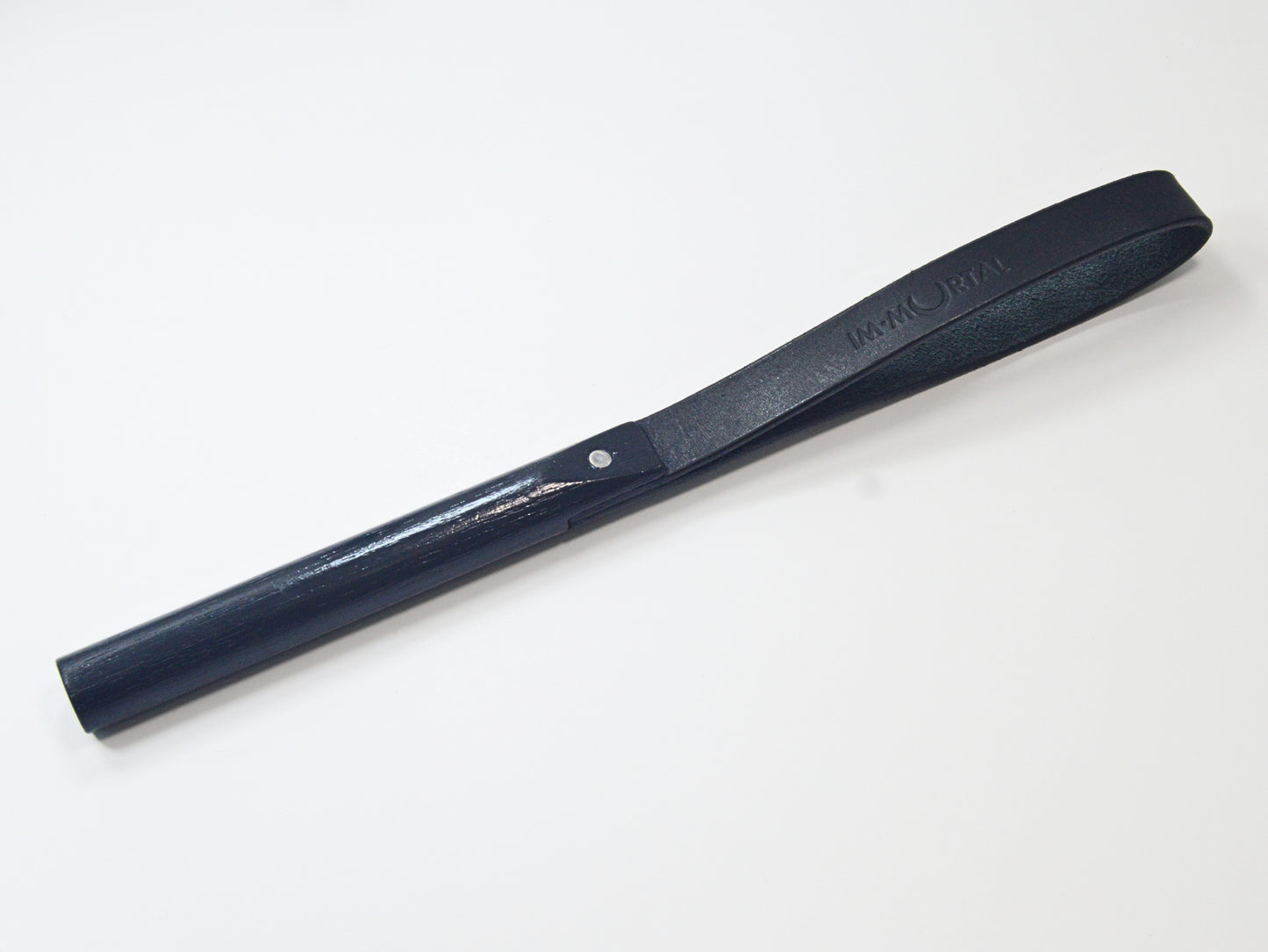 A black leather slapstick embossed with the word "IMMORTAL" with a wooden handle, showcased against a white background. It's designed for impact play.