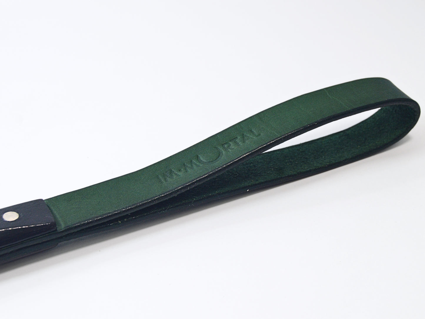 An anged, close-up shot of the green leather slapstick strap embossed with the word "IMMORTAL" showcased against a white background.