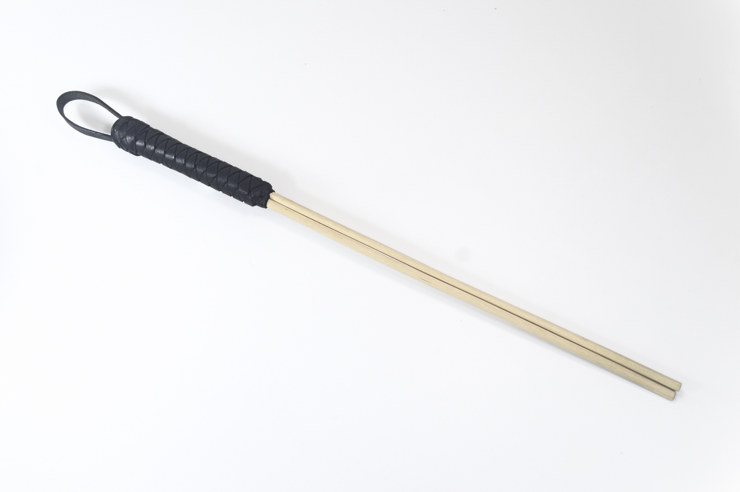 A aeriel shot of our black leather wrapped handled BDSM whip with two long, thin, tan canes against white background.